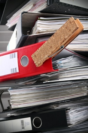 A red folder in a tower of black ones