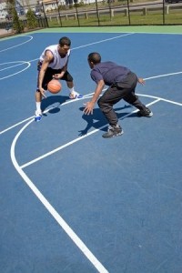 A young basketball player guarding his opponent during a one on one basketball game.
