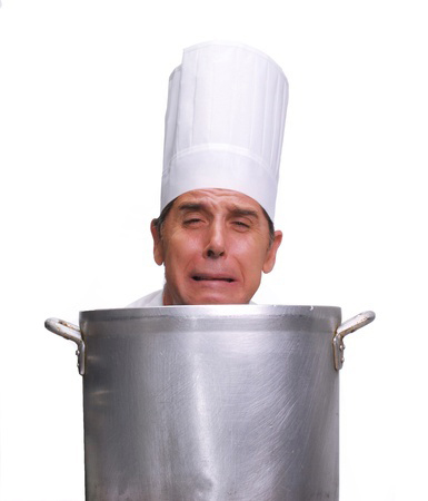 Cook looking upset behind a large pot on white background