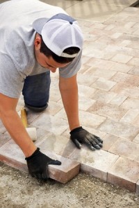Landscaping concept man, worker or trade putting down paver stones, vertical
