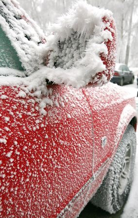Red car with outside mirror covered of icing