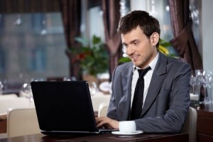 Business man with the laptop sits at a table in cafe