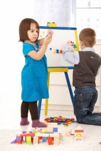 Children playing with magnetic drawing board and alphabet