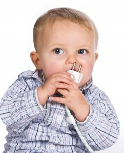 Curious baby playing a dangerous game with an electric plug