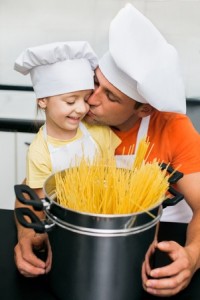 Father with daughter preparing spaghetti in kitchen