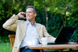 Healthy mature businessman working outdoor with mobile and laptop