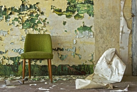 Old chair stands in front of a flaked off wall