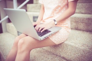 Young woman using laptop on steps outdoors
