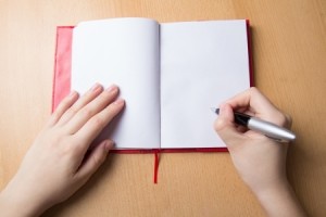 female hands with pen and notebook on desk