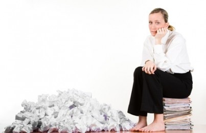 oman with pile of crumpled papers sitting on a stack of paperwork