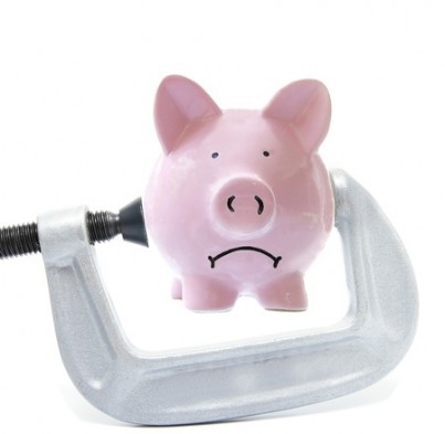 Sad piggy bank being squeezed in a vice