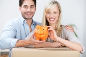 Smiling attractive young couple with a cute orange piggy bank