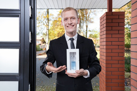 Smiling salesman standing at the door and selling perfume