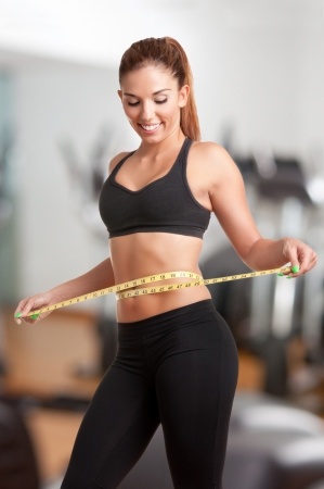 Woman measuring her waist with a yellow measuring tape