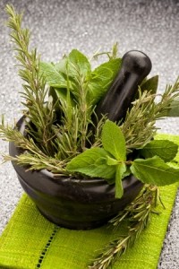 photo of fresh aromatic herbs in a mortar on glass table with black background