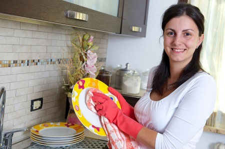 Beautiful brunette woman washing the dishes in the kitchen, Italy