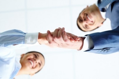 Below angle of successful associates handshaking after striking deal