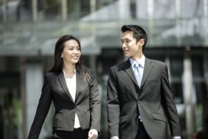 Happy Chinese Business colleagues walking outside office & talking to each other.