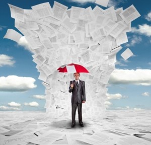 Serious businessman with red umbrella under huge wave of documents