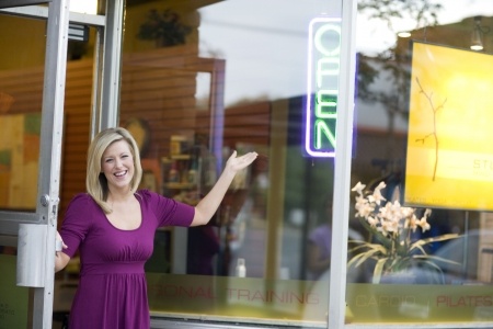 A happy business owner opening her shop door