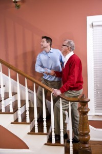 Man helping senior father climb staircase at home