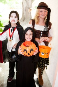 Three kids in Halloween costumes going trick or treating