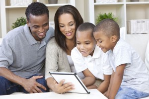 African American family, mother & father parents and two sons, having fun using a tablet computer together at home