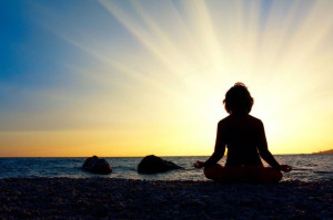 Silhouette of a woman meditating by the sea