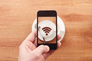 Smartphone taking photograph of free wifi sign on a latte coffee in a bar