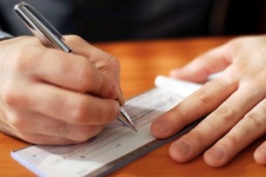 closeup on mans hands writing check