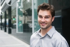 Portrait of a happy young businessman in suit standing outside office