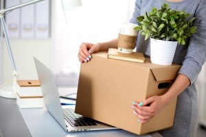 Happy team of businesspeople moving office, packing boxes, smiling