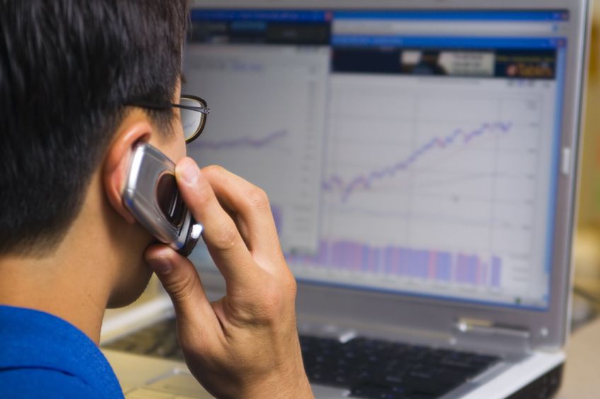 stock broker calling his client while looking at computer stock chart