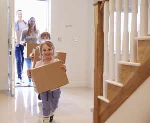 Family Carrying Boxes Into New Home On Moving Day