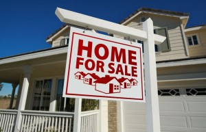 8644008 - red home for sale real estate sign and house against a blue sky.