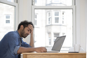 31164419 - stressed and frustrated asian man sitting at his laptop.