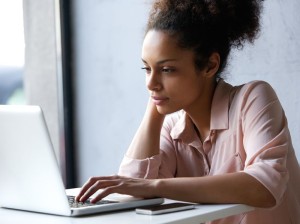 33727867 - close up portrait of a young black woman looking at laptop