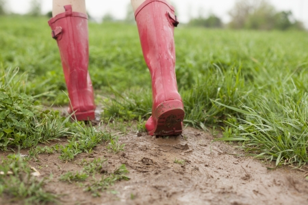 15842426 - a pair of pink rain boots walk through a muddy patch of grass
