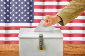 47062864 - man putting a ballot into a voting box - usa