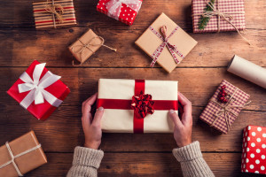 47169675 - man holding christmas presents laid on a wooden table background
