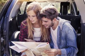 48213820 - young lovers looking map sitting in the trunk of car