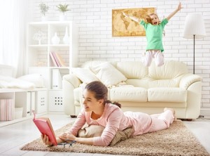 49591179 - family relax. mother reading a book and child jumping on the sofa.