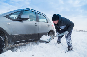 52263541 - man shoveling snow to free his stuck car