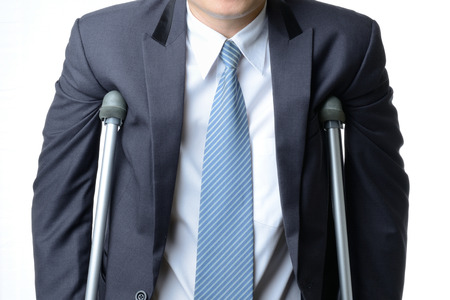 injured businessman in with crutches isolated on white background, insurance concept