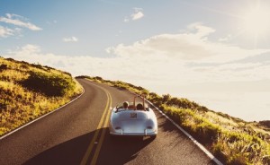 44182169 - happy couple driving on country road in classic vintage sports car