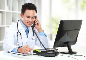 12809550 - smiling male doctor busy working at his desk