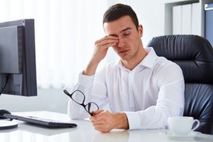 40285290 - young tired businessman rubbing his eye in the office
