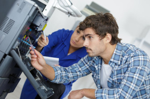 83135634 - two young technicians repairing printer