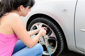 14301097 - young woman checking pressure and inflating car tires