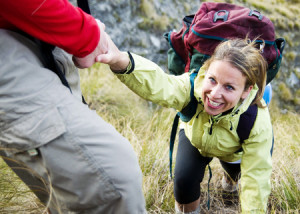 31336446 - hikers helping each other up a mountain.